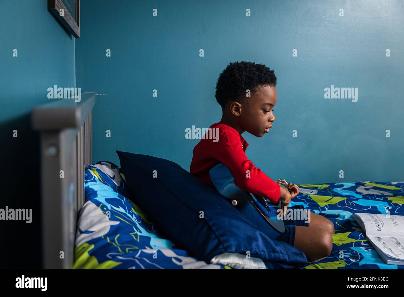 Vista laterale della simpatica chitarra che impara a casa Foto Stock