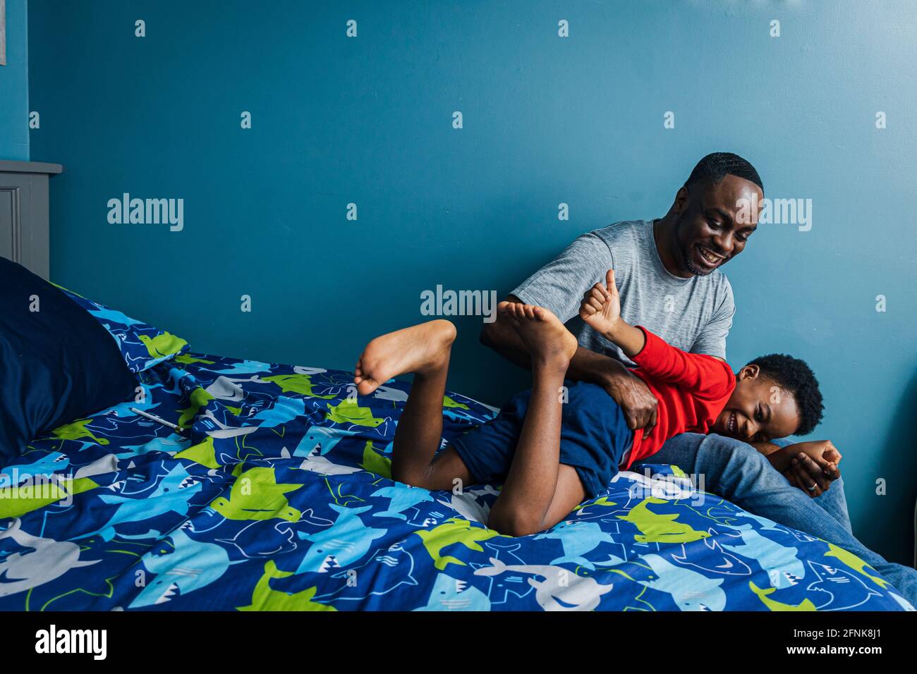 Il padre e il figlio giocosi a letto trascorrono il tempo libero insieme a casa Foto Stock