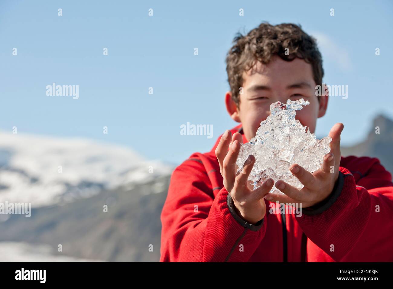 Ragazzo adolescente che tiene il ghiaccio dalla laguna del ghiacciaio in Islanda Foto Stock