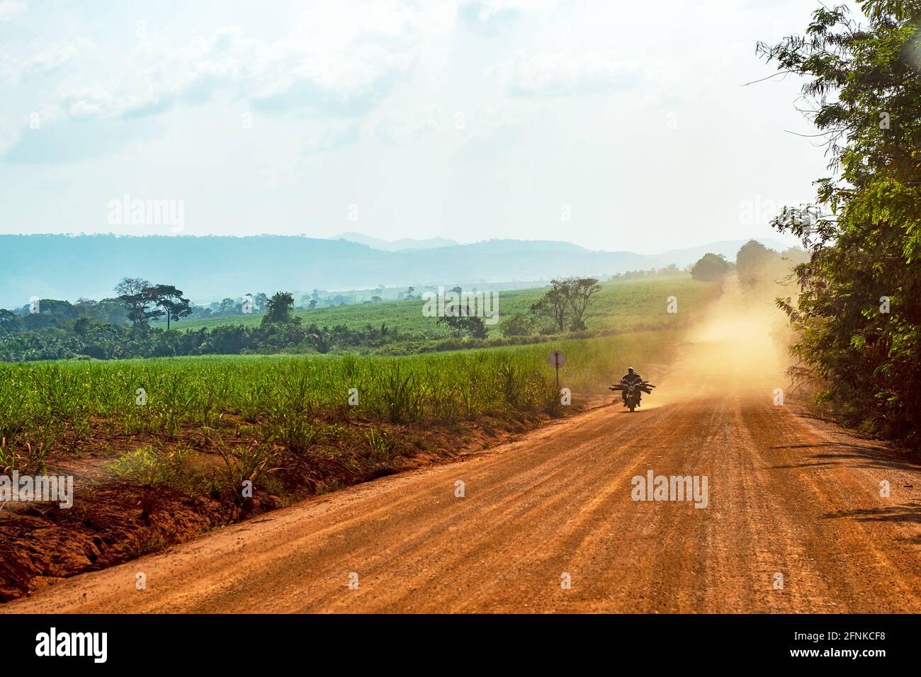 Motociclista su una strada polverosa in Africa Foto Stock