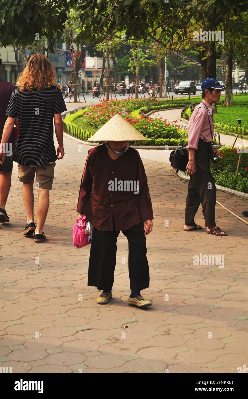 Donne anziane vietnamite che camminano sul sentiero pedonale accanto Hoan Kiem stagno giardino o lago della Sword restituito pubblico park andare a Hoan Kiem squa Foto Stock