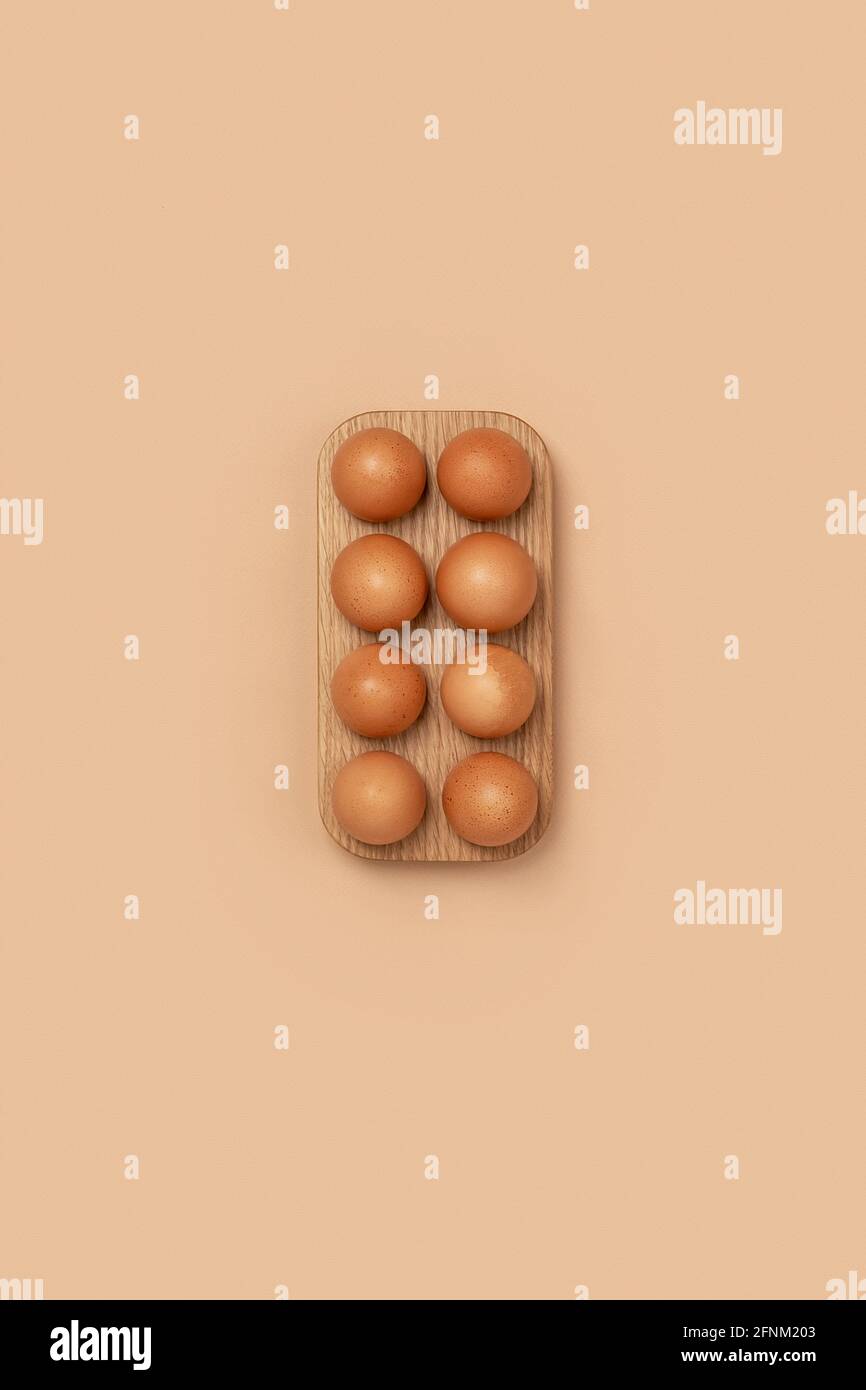Uova naturali biologiche in scatola di uova di legno su sfondo beige. Composizioni in colori monocromatici. Concetto di zero sprechi. Foto Stock
