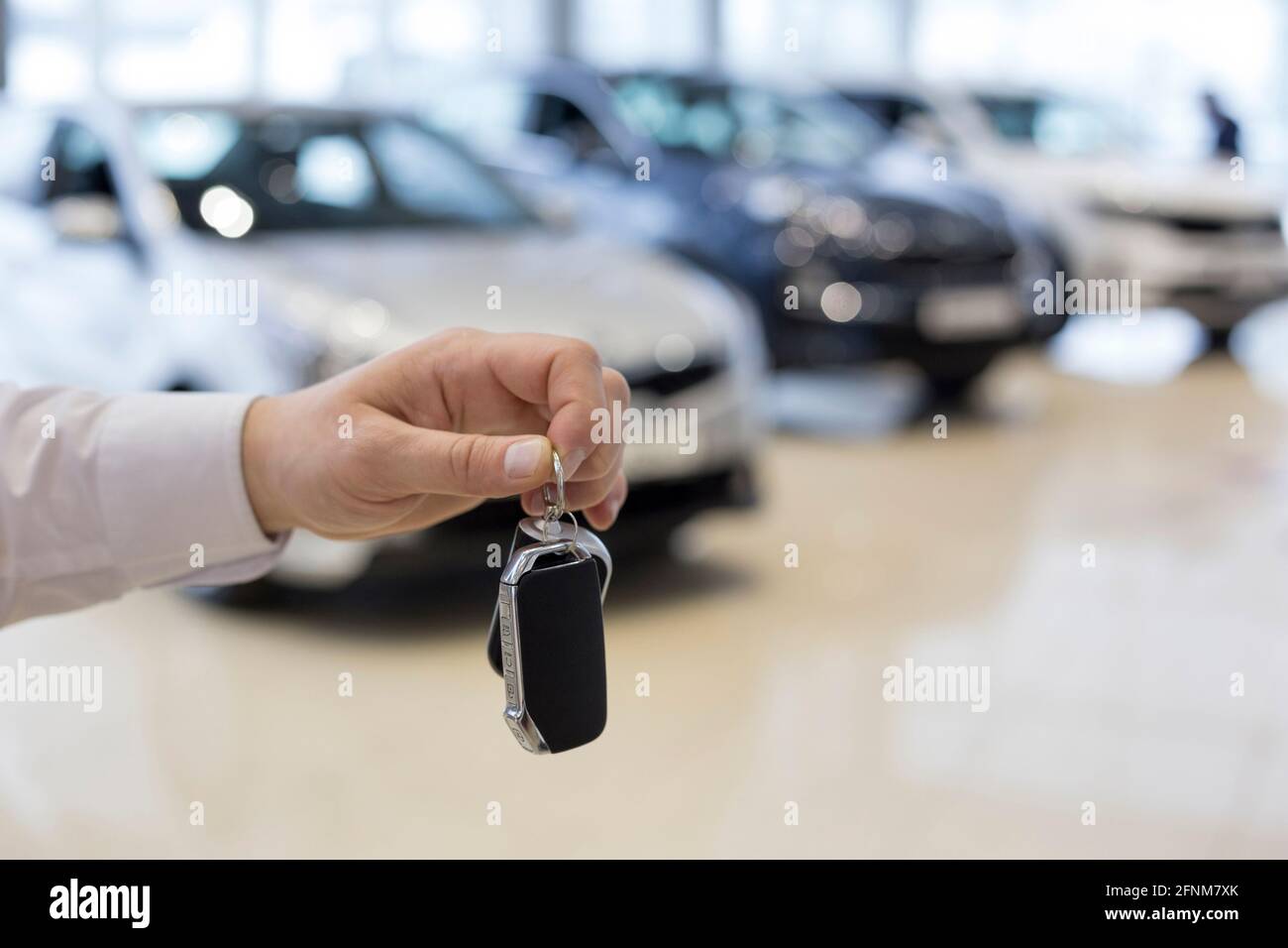 Venditore che tiene le chiavi di una nuova auto. Concessionaria auto. Veicoli moderni e prestigiosi. Foto Stock
