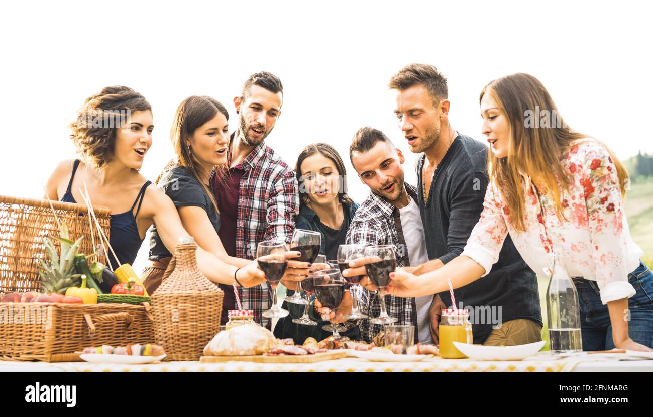 Giovani amici divertirsi all'aperto bevendo vino rosso al barbecue - gente felice che mangia cibo sano al momento del raccolto dentro azienda agricola vigneto Foto Stock