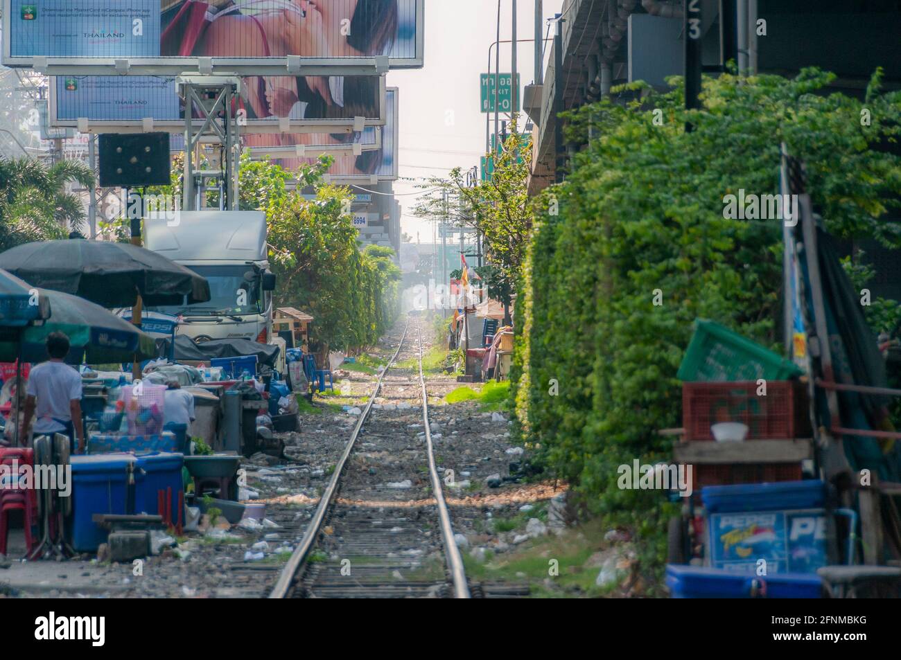 Le bancarelle del mercato e le case del ramphackle si trovano accanto a una linea ferroviaria a Bangkok in Thailandia nel Sud Est asiatico. Foto Stock