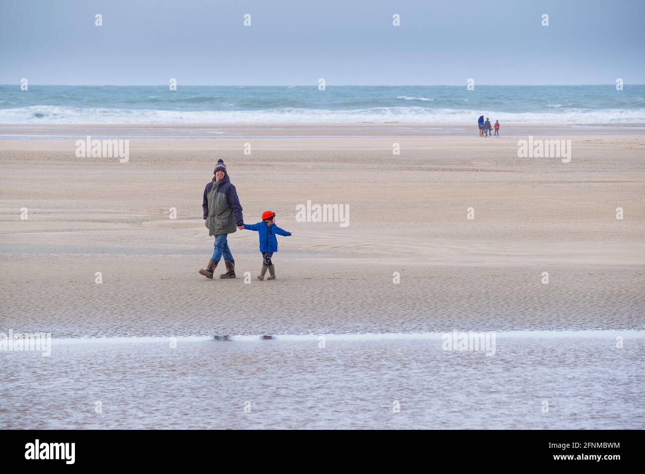 Un padre e un bambino che si godono una passeggiata su una spiaggia fredda Crantock a Newquay in Cornovaglia. Foto Stock