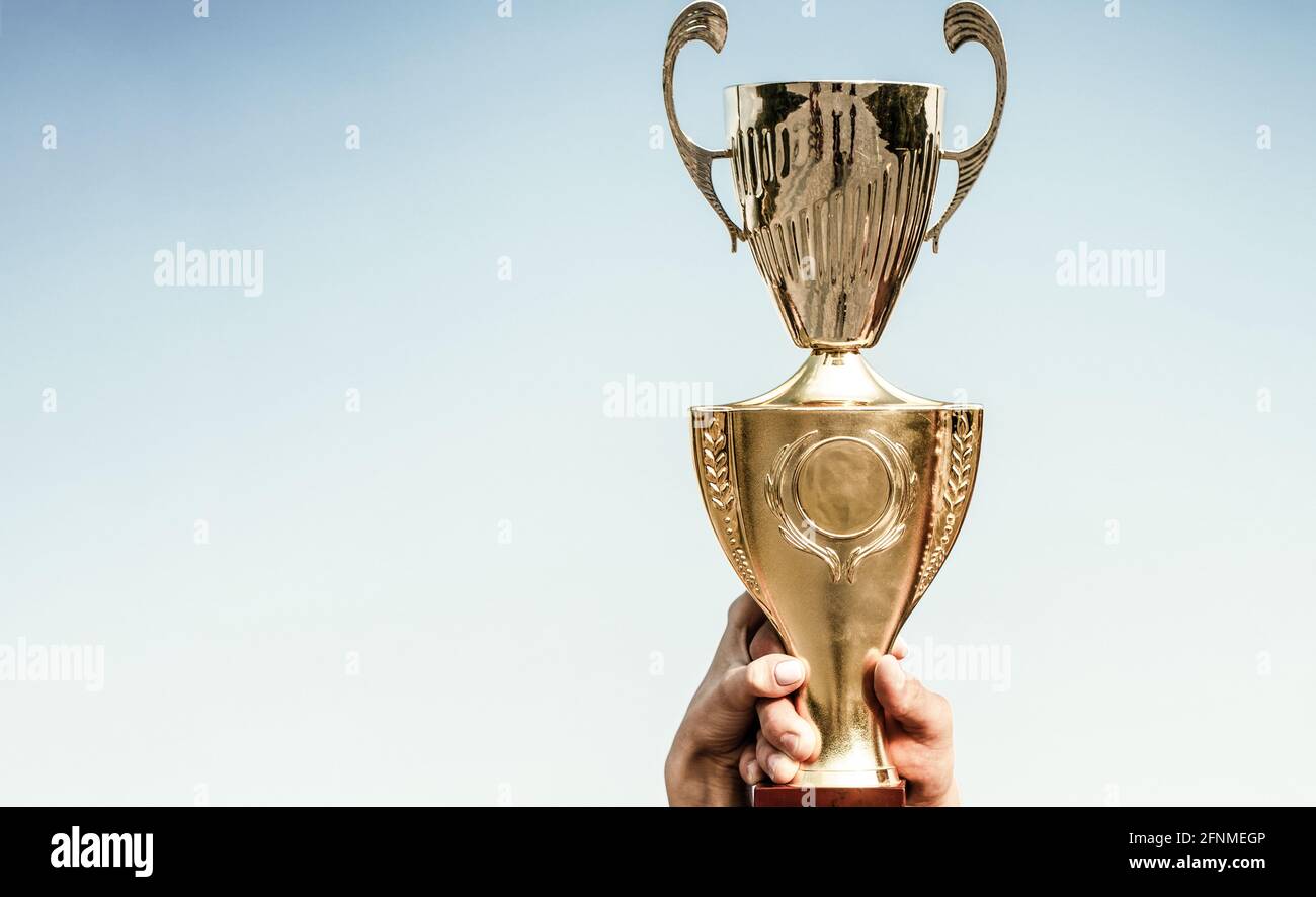 Vincitori che tengono trofei d'oro campione. Mano della persona con un trofeo sportivo. Coppa del trofeo d'oro come vincitore. Campione professionista. Squadra dei vincitori Foto Stock