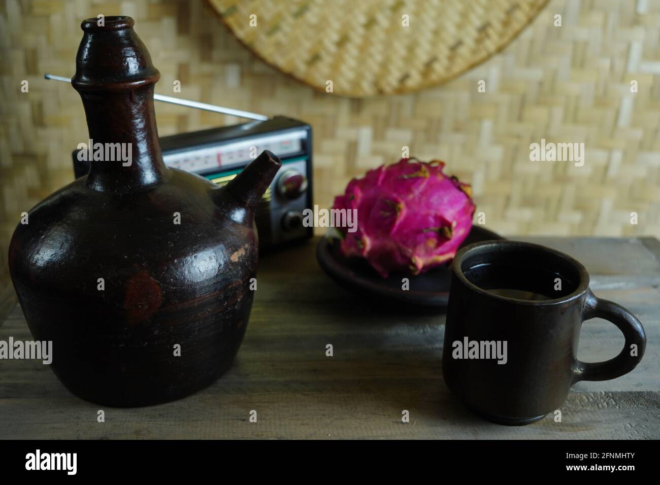 Caraffa di vino in ceramica, tazza, vecchia radio e frutta di drago su un tavolo Foto Stock