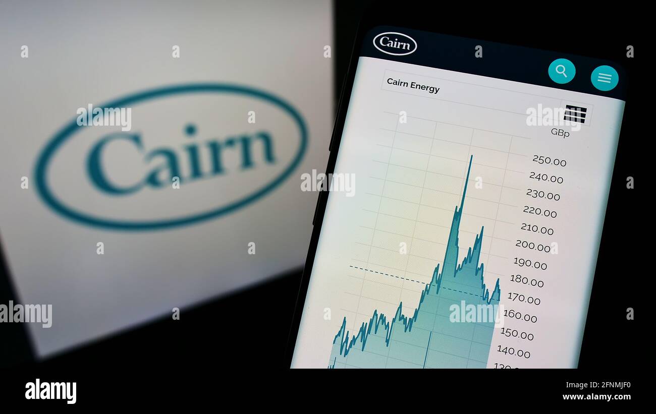 Persona che detiene cellulare con sito web e stock chart della società di petrolio e gas Cairn Energy plc sullo schermo con logo. Mettere a fuoco il centro del display del telefono. Foto Stock