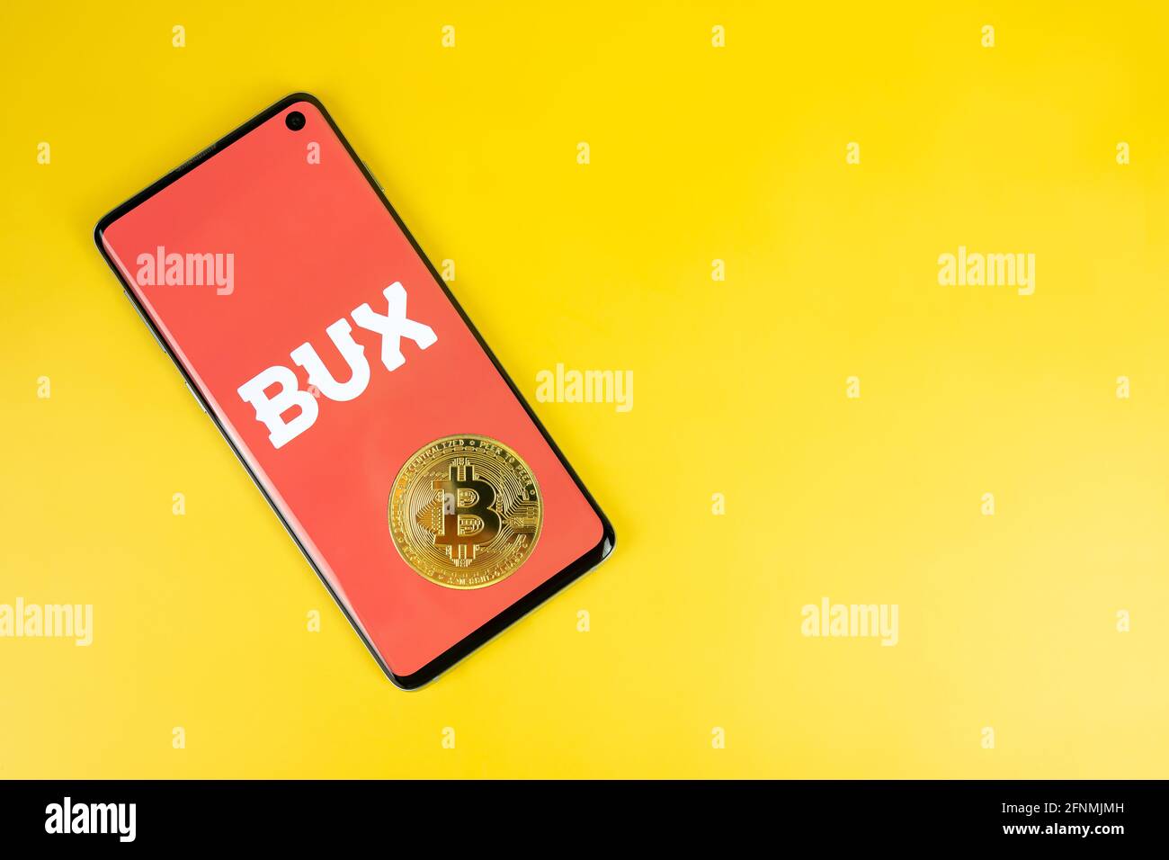 SWANSEA, UK - 4 MAGGIO 2021: Smartphone con logo Bux con moneta Bitcoin su sfondo giallo. App di investimento mobile, società di brokeraggio in Europa Foto Stock
