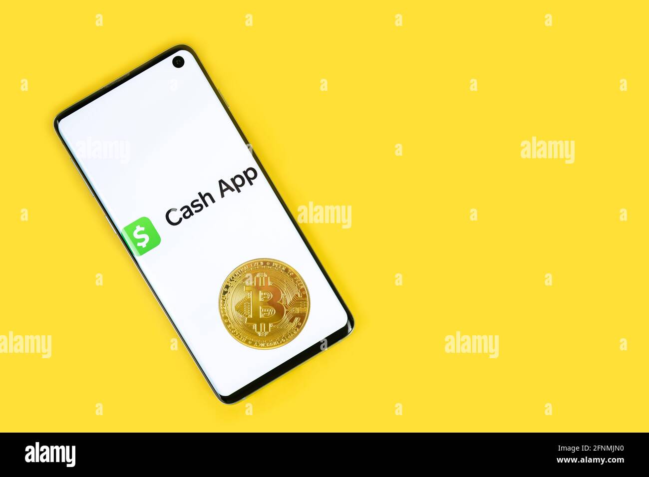 SWANSEA, UK - 4 MAGGIO 2021: Smartphone con logo Cash App con moneta Bitcoin su sfondo giallo. Servizio di pagamento mobile, investendo in criptovalute Foto Stock