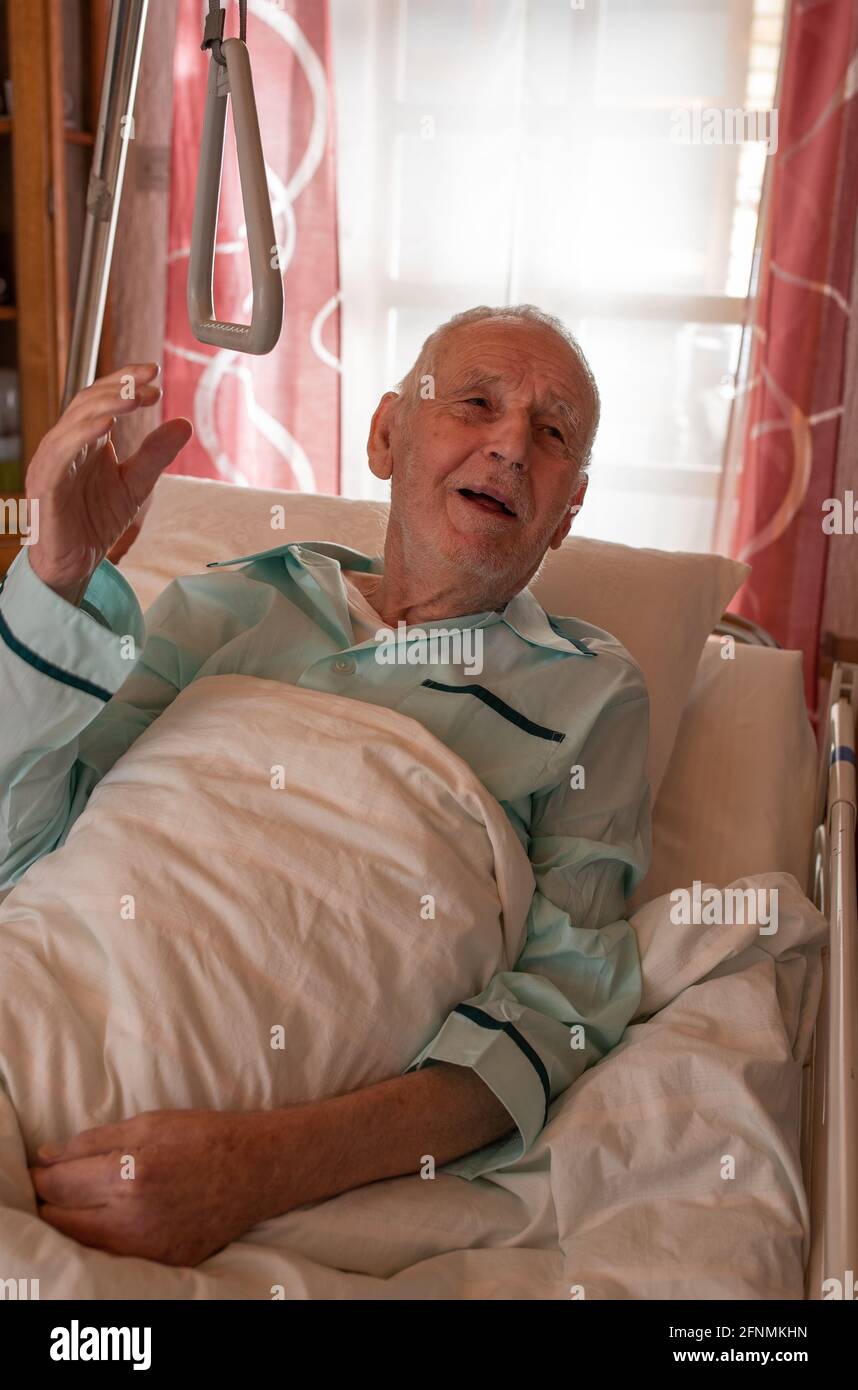 Anziano negli anni 80 seduto in letto medico in ospedale. Concetto di assistenza geriatrica e sanitaria Foto Stock