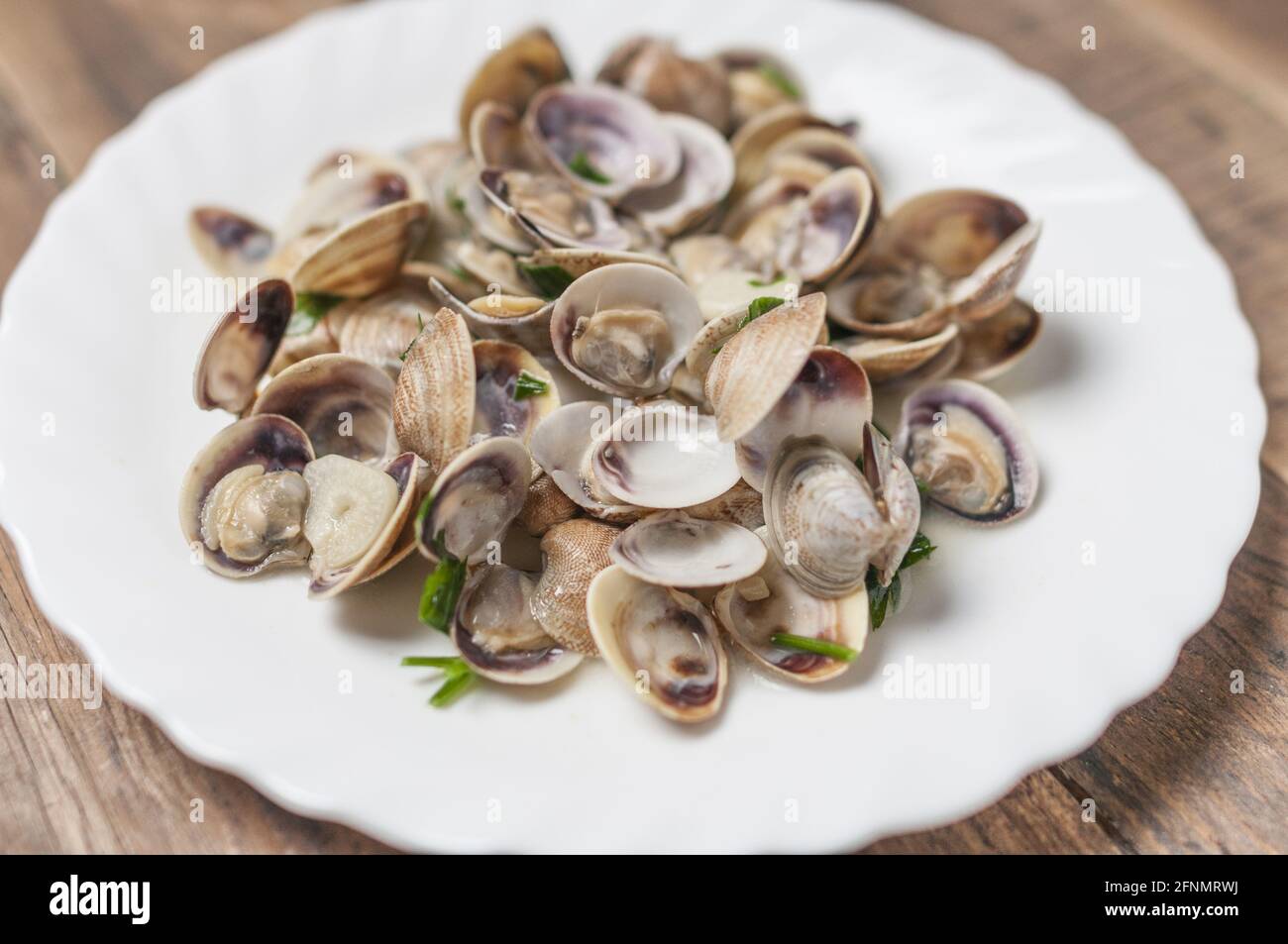 Piatto con vongole in salsa di vino con aglio e prezzemolo Foto Stock