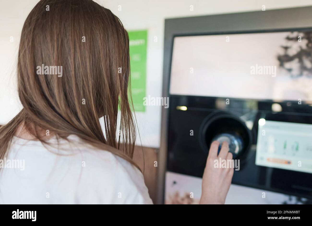 Donna mette il flacone in una macchina automatica per il riciclaggio delle bottiglie. Macchina per il riciclaggio con distributori automatici a inversione. Foto Stock