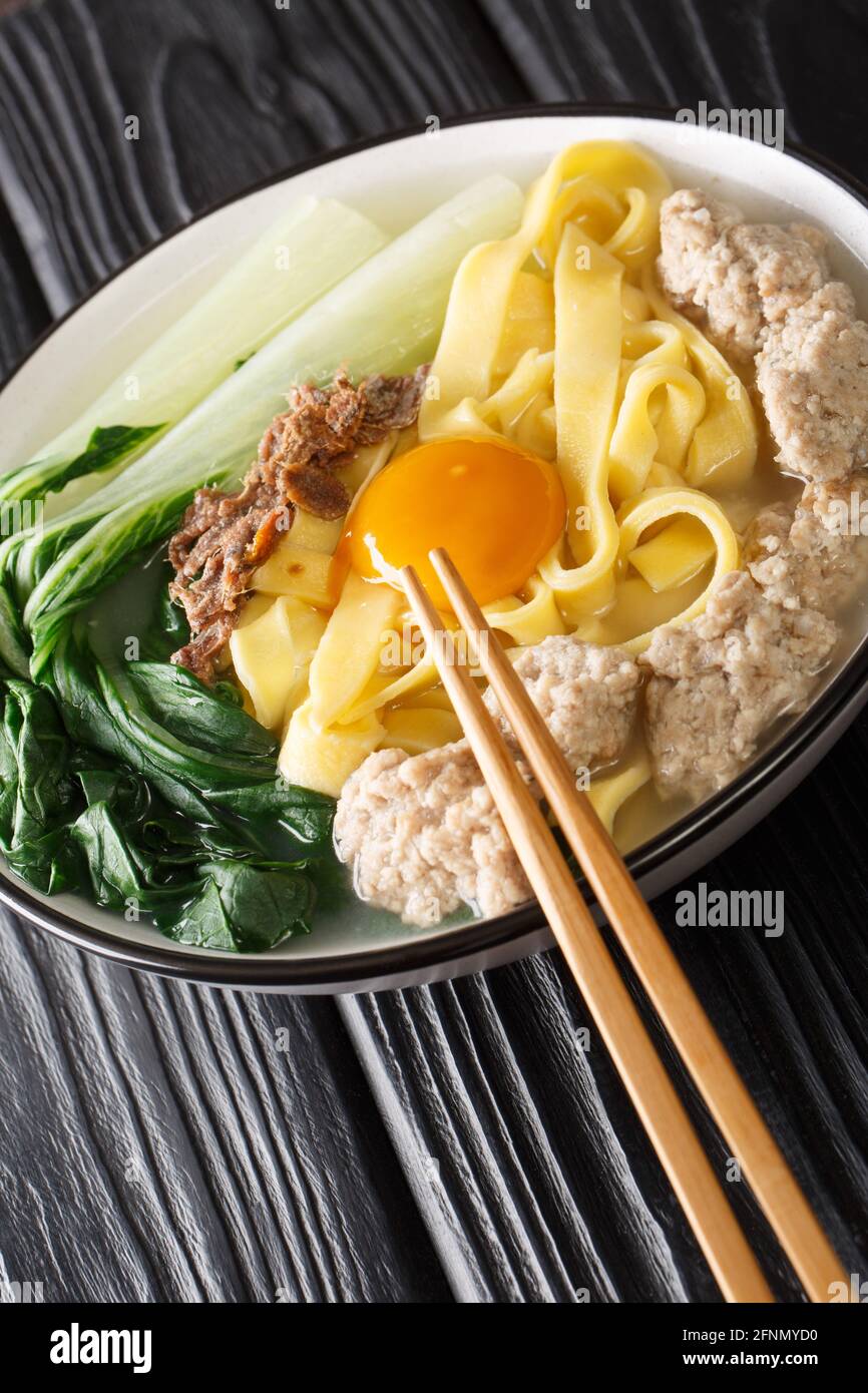 Ban Mian minato maiale Noodle zuppa di preparazione del primo piano fatto a mano nella ciotola sul tavolo. Verticale Foto Stock