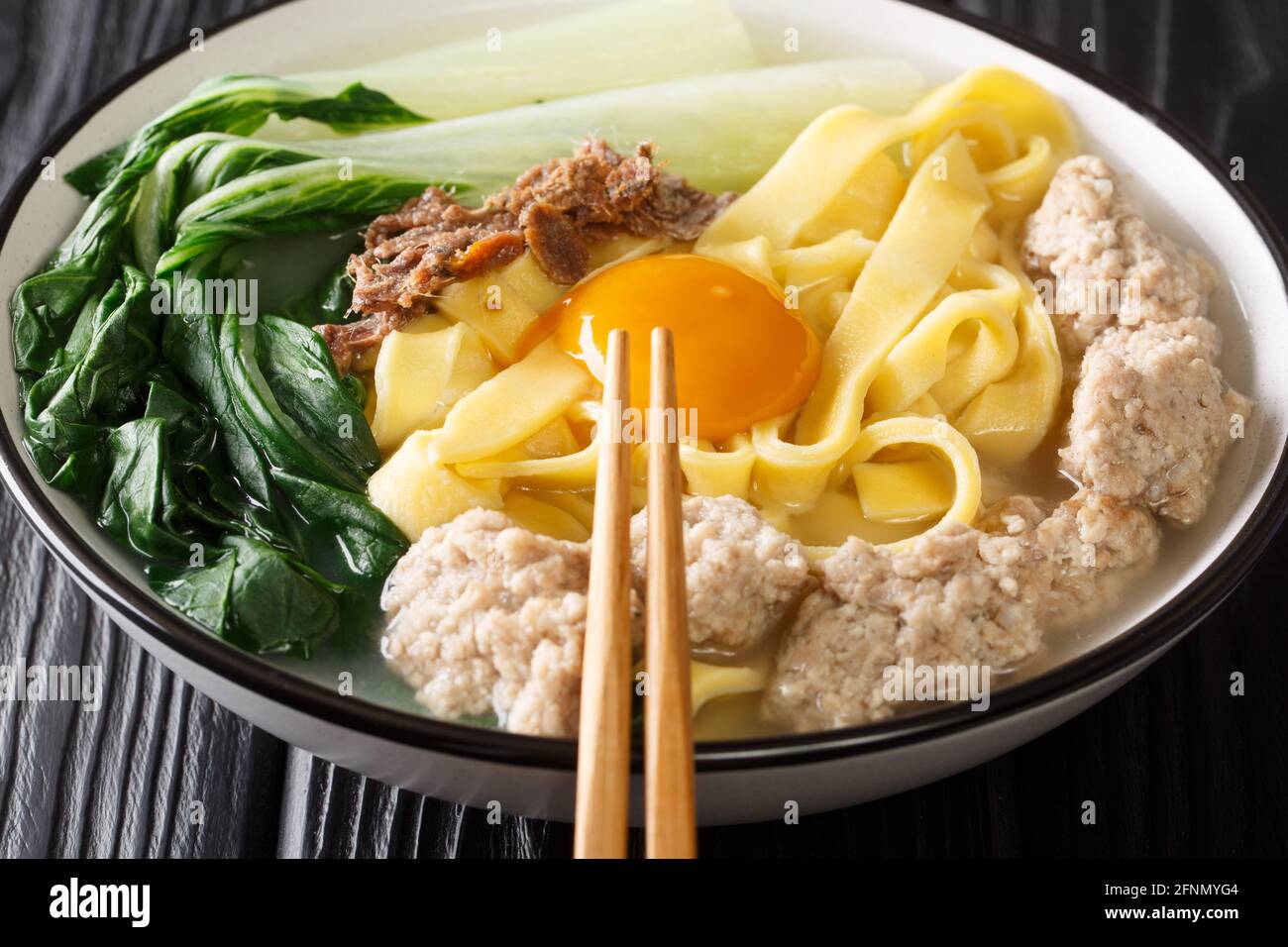 Ban Mian Singaporean favorito, questi spessi, noodle di uova fatte a mano cucinati in un primo piano di zuppa salata nella ciotola sul tavolo. Orizzontale Foto Stock
