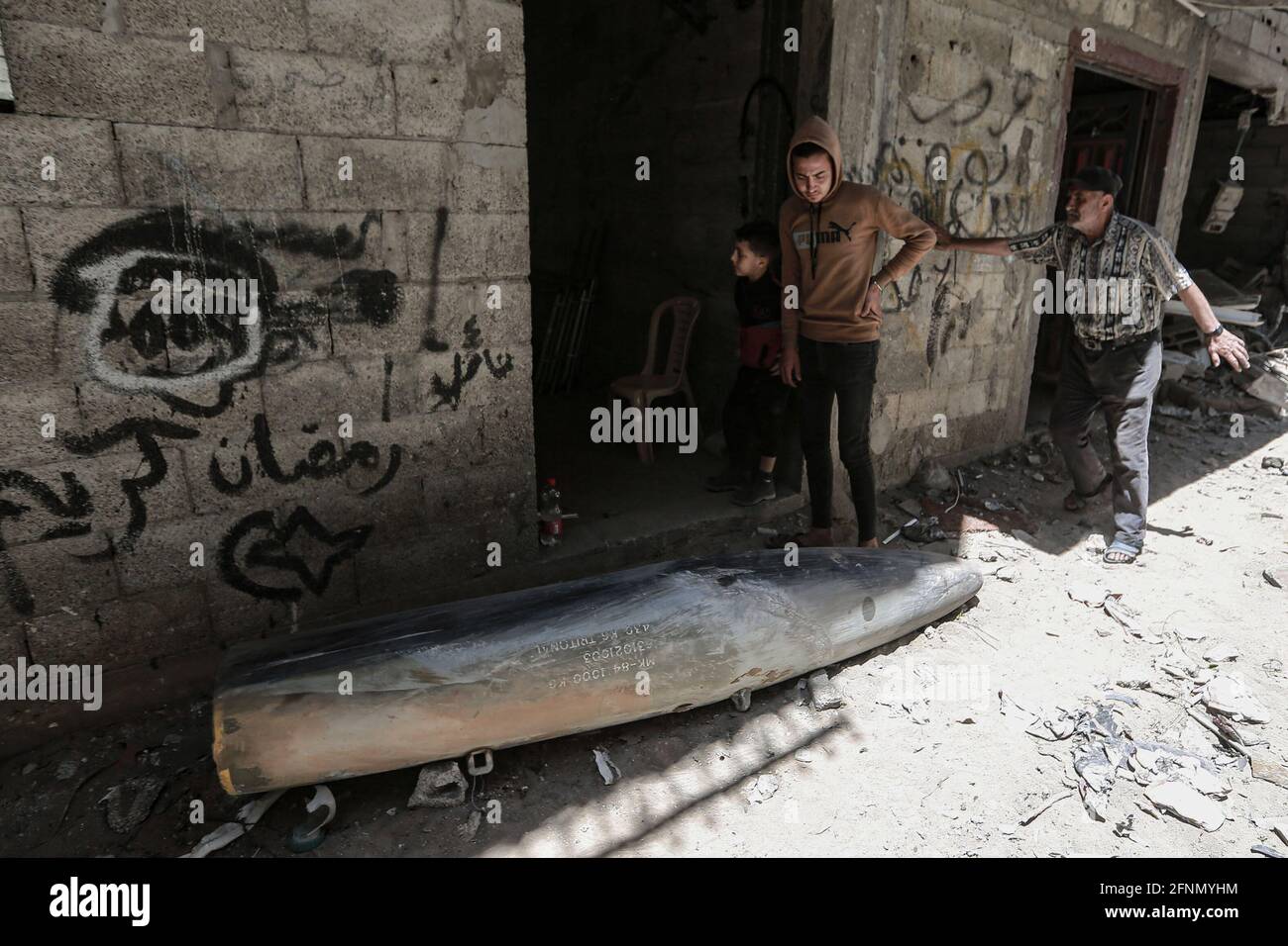 Gaza, territori palestinesi. 18 maggio 2021. I palestinesi ispezionano una bomba inesplosa caduta da un aereo da guerra israeliano F-16 nel quartiere di Rimal, in mezzo all'escalation della violenza israelo-palestinese. Credit: Mohammed Talatene/dpa/Alamy Live News Foto Stock