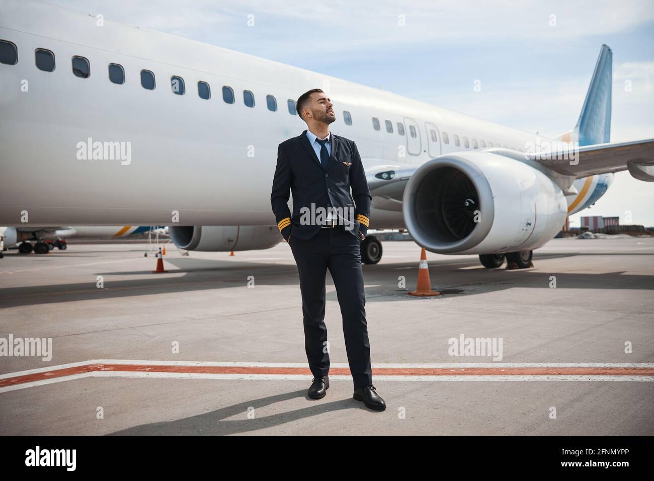 Pilota che guarda lontano mentre si è in piedi sulla pista vicino all'aereo Foto Stock