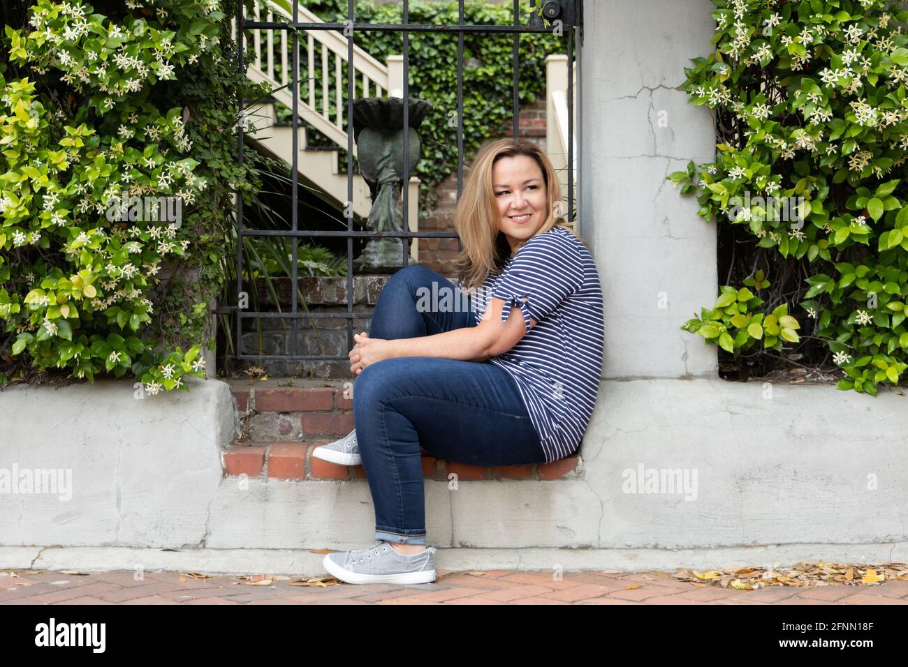 Una sola donna nel suo 40's seduto fuori a Savannah, Georgia in primavera guardando via Foto Stock