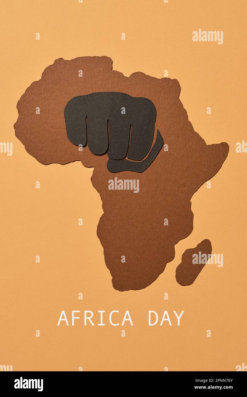 la silhouette dell'africa, ritagliata da un foglio a motivi geometrici, un pugno tagliato e il testo happy africa giorno su uno sfondo marrone Foto Stock
