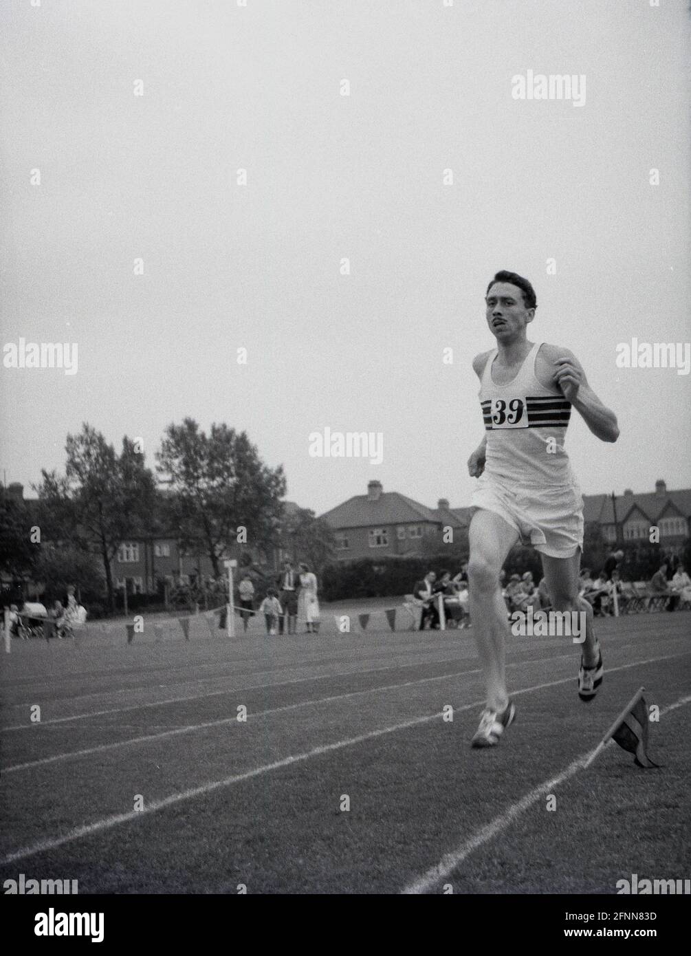 1954, storico, un concorrente maschile fuori correre su una pista di erba in una giornata di sport di servizio civile, Inghilterra, Regno Unito, un evento sportivo dilettante ma comunque competitivo. Foto Stock