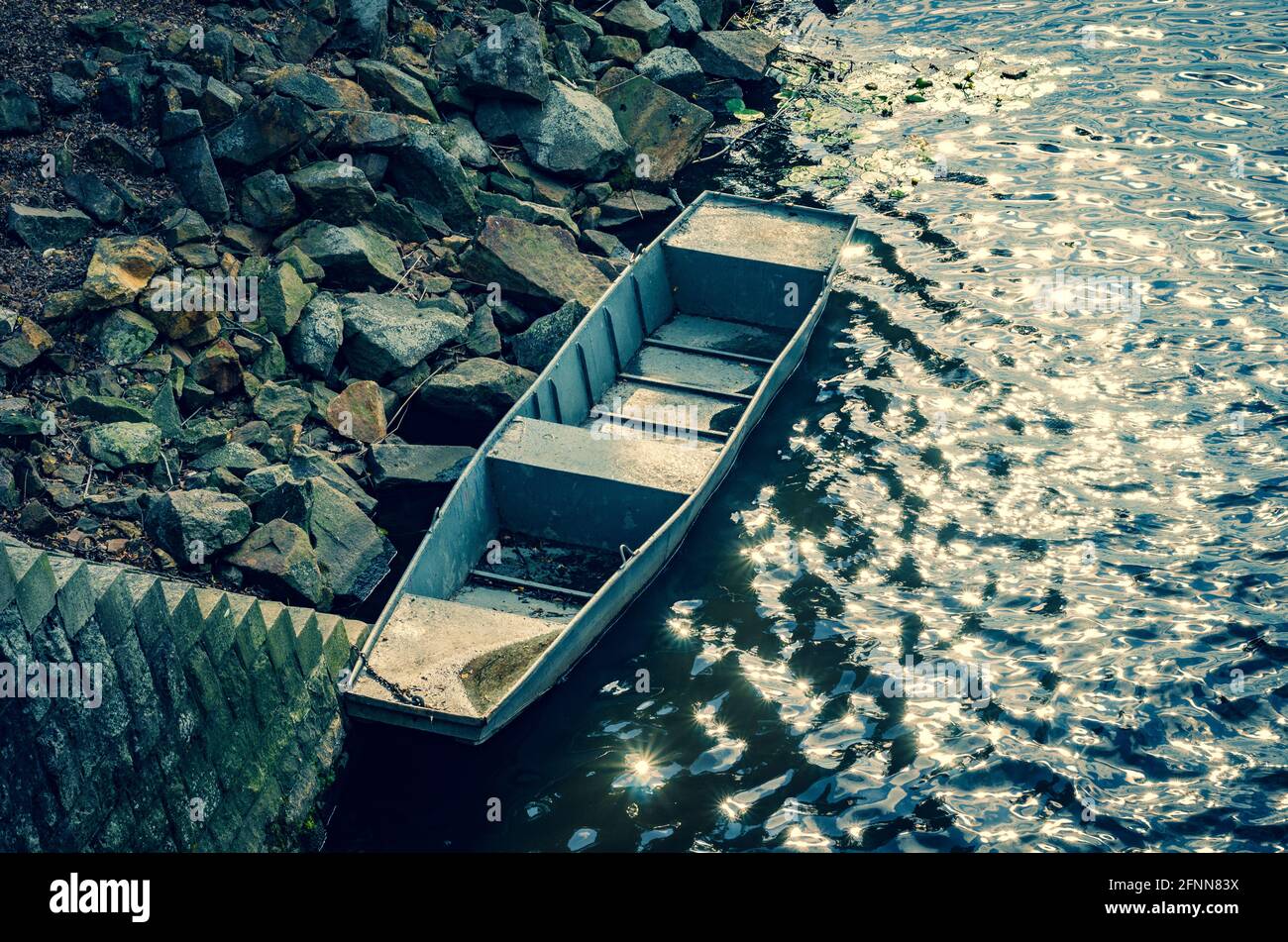 Vecchia barca in metallo ormeggiata su una riva rocciosa Foto Stock