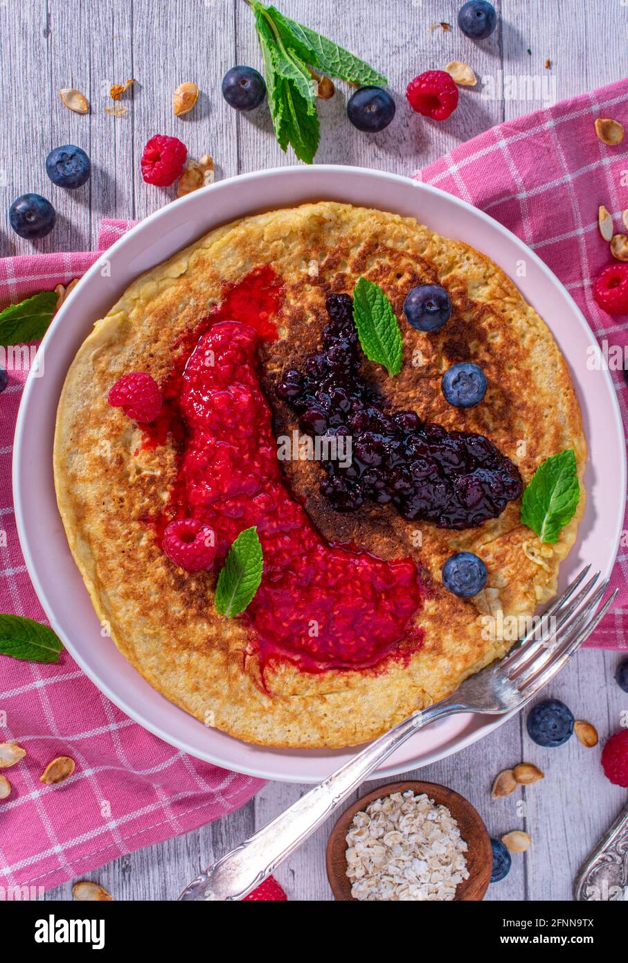 Sana colazione pancake fatto con farinata d'avena senza glutine e servita con purea di frutti di bosco freschi su un piatto. Foto Stock