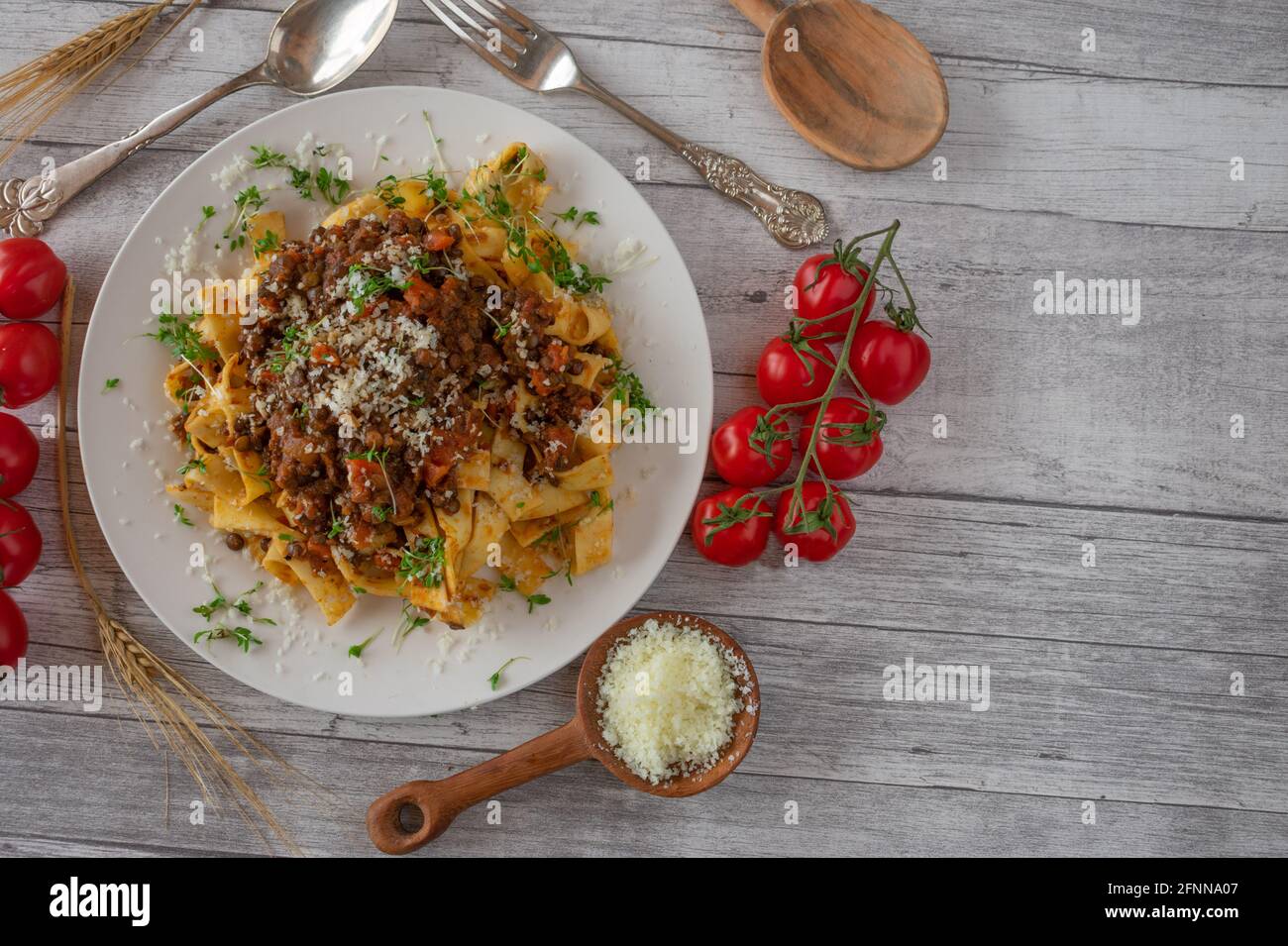 lenticchie bolognesi vegetariane con parmigiano servite su un piatto bianco su rustico fondo di tavola in legno. Vista dall'alto con spazio per la copia Foto Stock