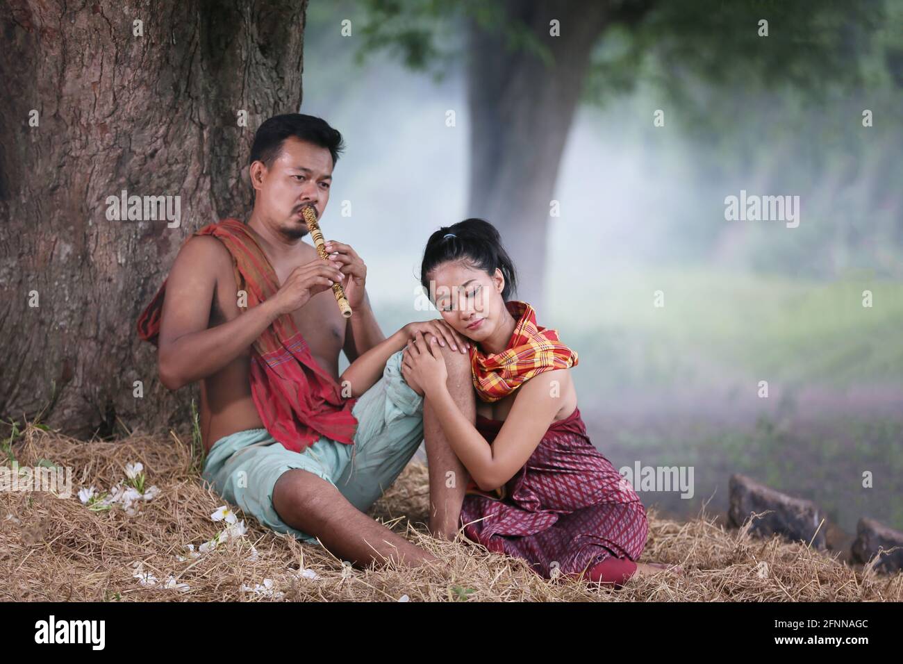 Coppia amore di giovani asiatici e donne seduti sotto l'albero contro bufali e sfondo naturale, stile di vita rurale nel nord-est della Thailandia. R Foto Stock