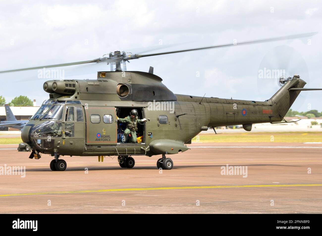 Royal Air Force, RAF, Puma HC.1 elicottero XW235 tassare a Royal International Air Tattoo, RIAT, RAF Fairford, Regno Unito. Uomo della creda che osserva per sicurezza Foto Stock