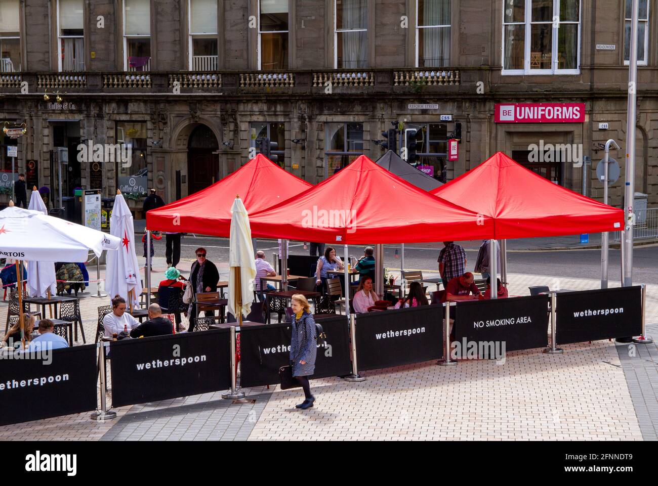 Dundee, Tayside, Scozia, Regno Unito. 18 maggio 2021. Regno Unito tempo: Caldo sole di primavera attraverso la Scozia nord-orientale con temperature che raggiungono i 15°C. Le restrizioni di blocco del Covid-19 sono ora rilassate al livello 2 a Dundee, vedendo le persone che approfittano delle nuove normative facilitate e socializzando all'interno e all'esterno dei pub locali. Le restrizioni di livello 2 consentono ai pub Dundee di rimanere aperti per affari fino alle 22:30 con i clienti che si godono il tempo bevendo e mangiando presso la casa pubblica J.D Wetherspoon`s Counting House. Credit: Dundee Photographics/Alamy Live News Foto Stock