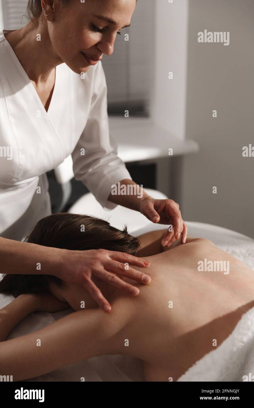 Donna che si rilassa al salone termale. Estetista che usa il raschiatore di gua sha per il massaggio della parte posteriore del corpo, terapeuta che fa la terapia di tsm asiatica del gouache per il cliente a. Foto Stock