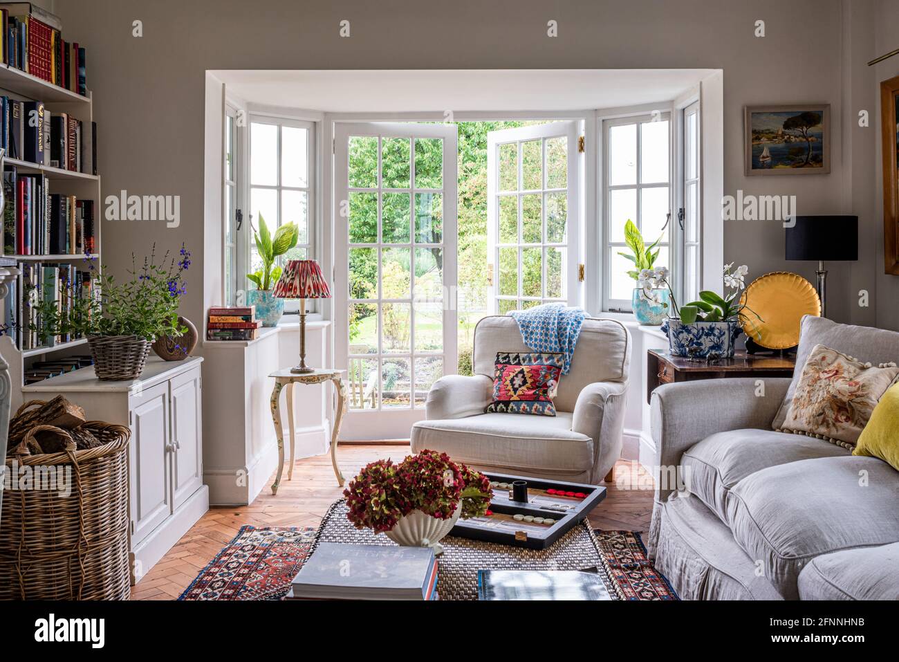 Suite a tre pezzi e libreria con porta aperta al giardino in cottage vittoriano del 19 ° secolo. Foto Stock