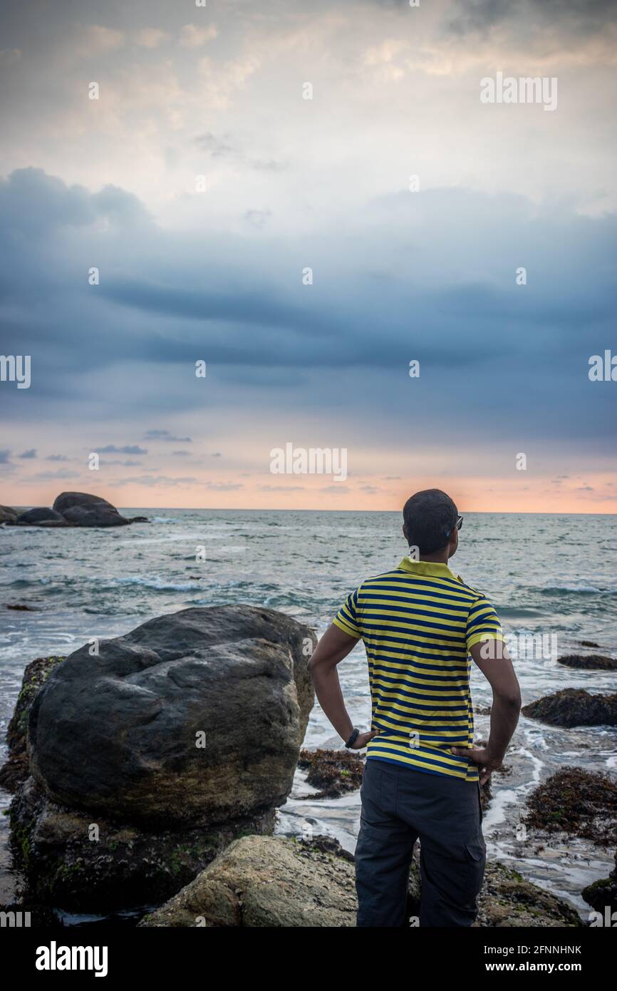 Uomo isolato guardando l'orizzonte del mare con cielo drammatico Foto Stock