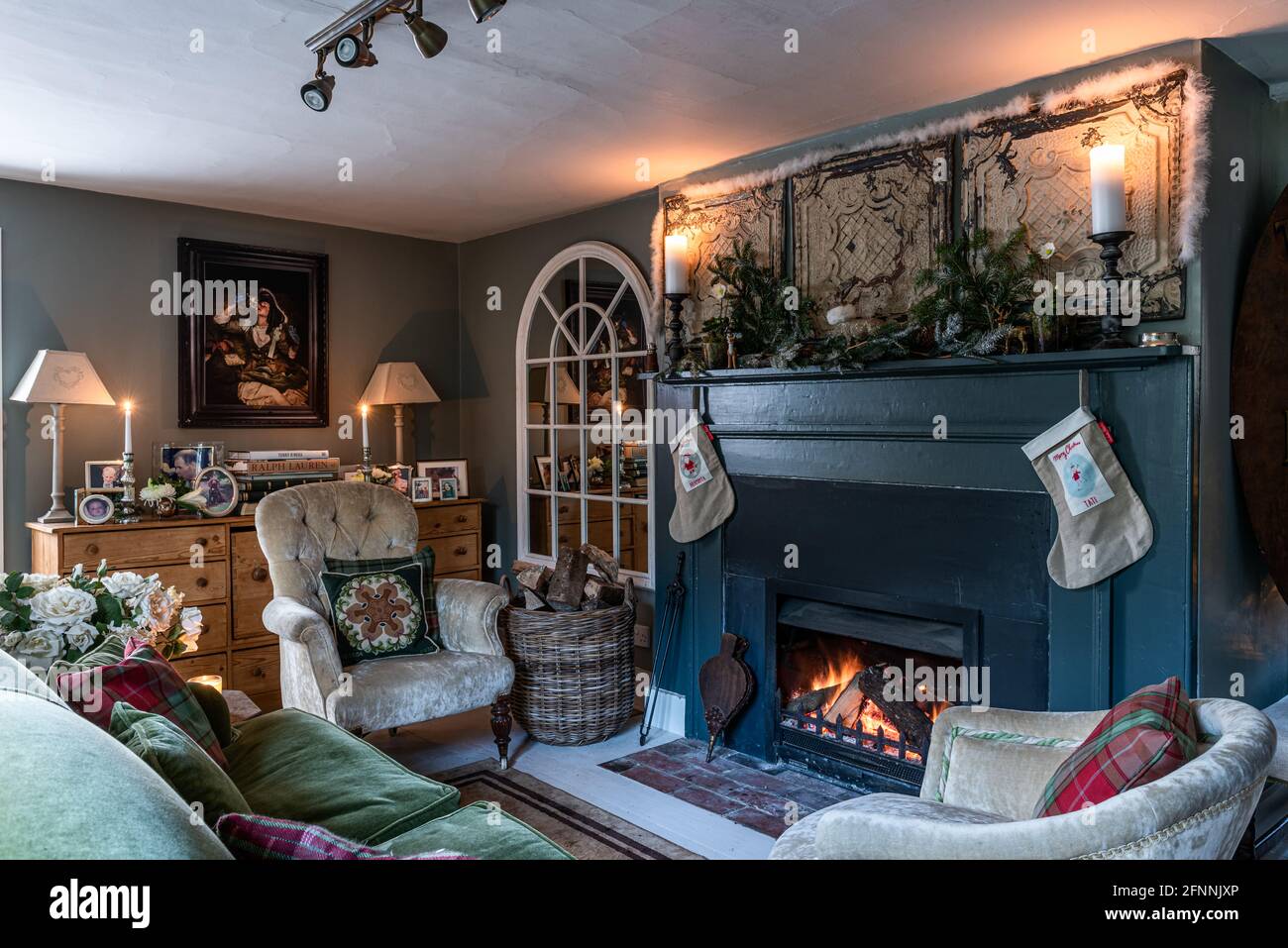 Candele accese sul camino in giù tubo con calze di Natale in cottage georgiano, Sussex occidentale. Foto Stock