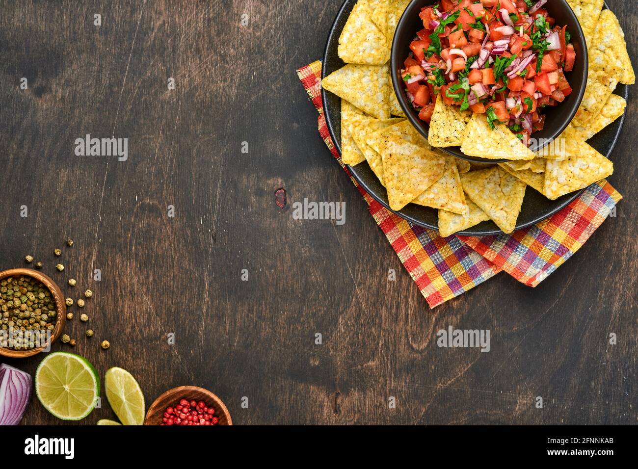 Salsa di pomodoro tradizionale messicana con nachos e ingredienti pomodori, cile, aglio, cipolla su sfondo scuro vecchio legno. Concetto di Amer Latina Foto Stock