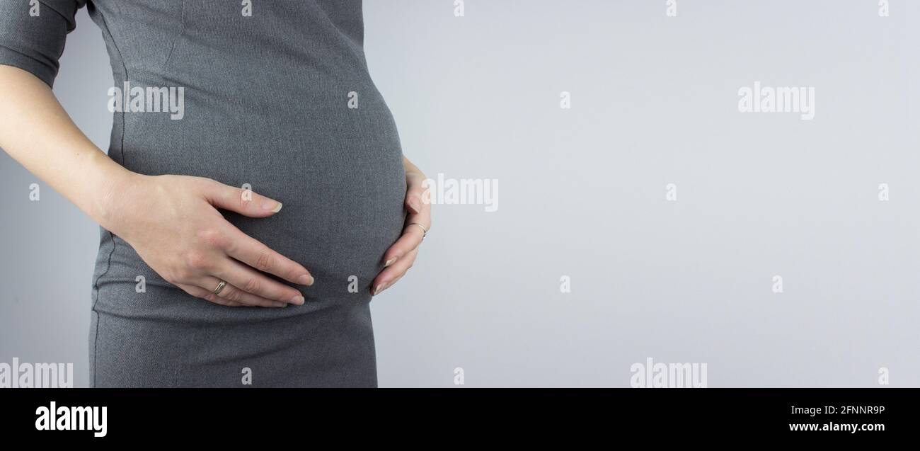 Giovane donna che tiene il ventre incinta in mani. Preparazione e concetto di aspettativa Foto Stock