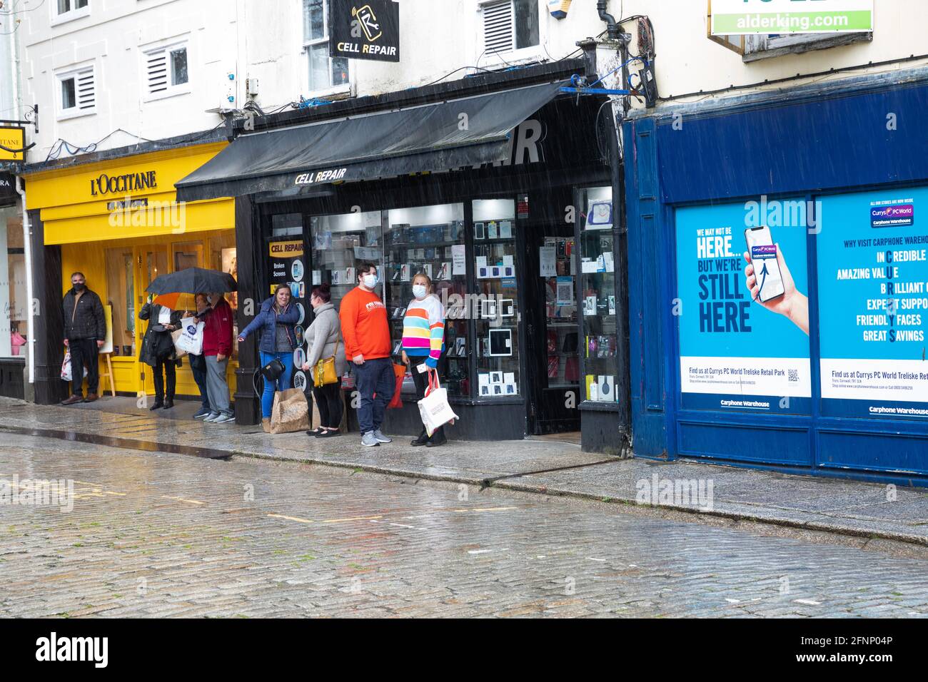 Truro, Regno Unito. 18 maggio 2021, persone riparate dalla pioggia pesante fuori da un negozio a Truro, Cornovaglia. La previsione è per 14C con intervalli di sole e una brezza gentile.Credit: Keith Larby/Alamy Live News Foto Stock