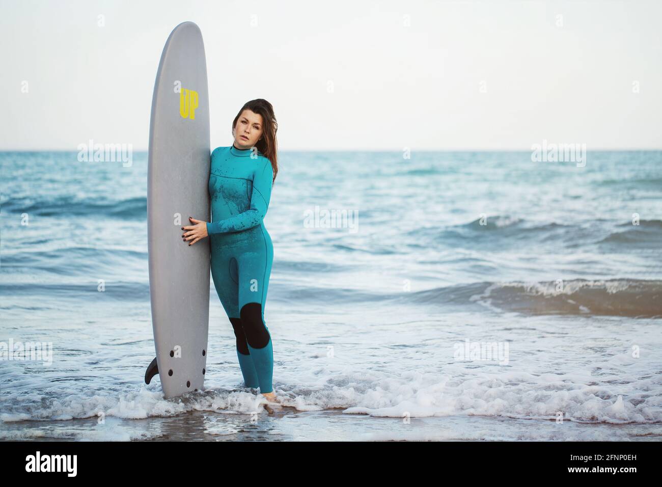 Surfer ragazza che cammina con bordo sulla spiaggia di sabbia. Surfer femminile.Beautiful giovane donna in spiaggia. Sport acquatici. Stile di vita attivo sano. Estate Foto Stock