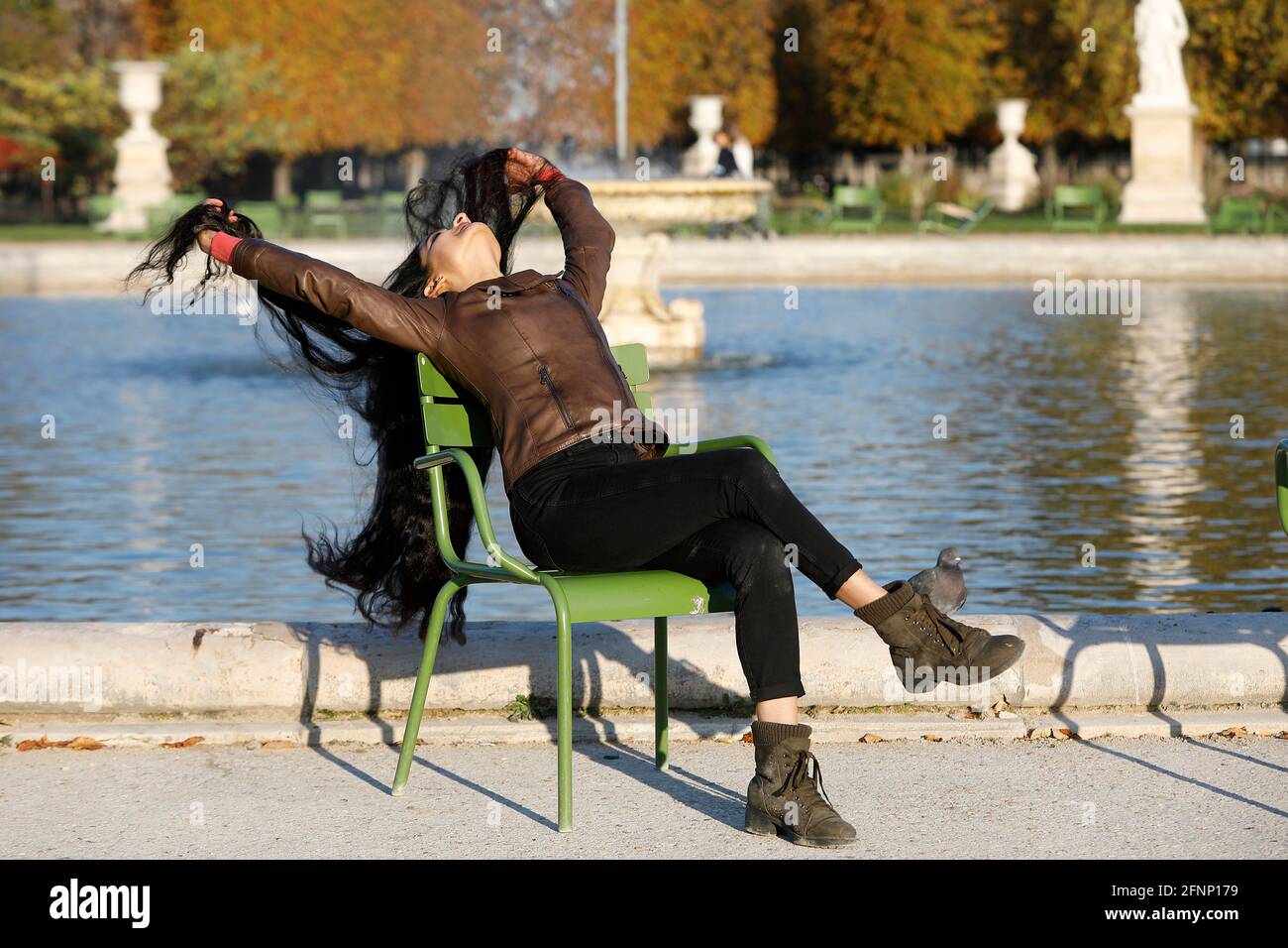 Giovane donna indiana seduta su una sedia in un parco a Parigi, Francia Foto Stock