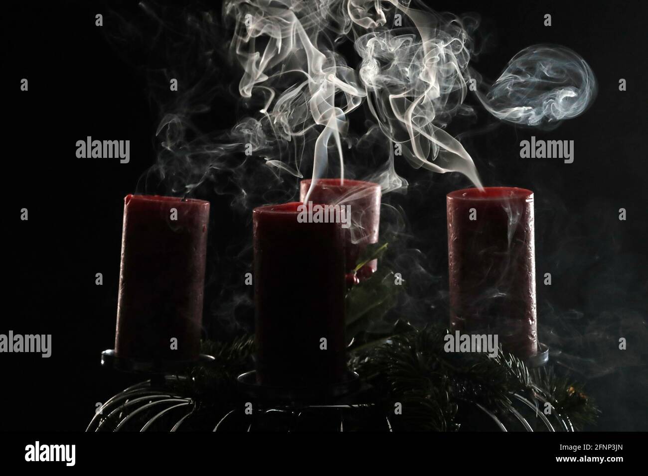 Fumo arricciante dalle candele dell'avvento spente su sfondo nero. Francia. Foto Stock