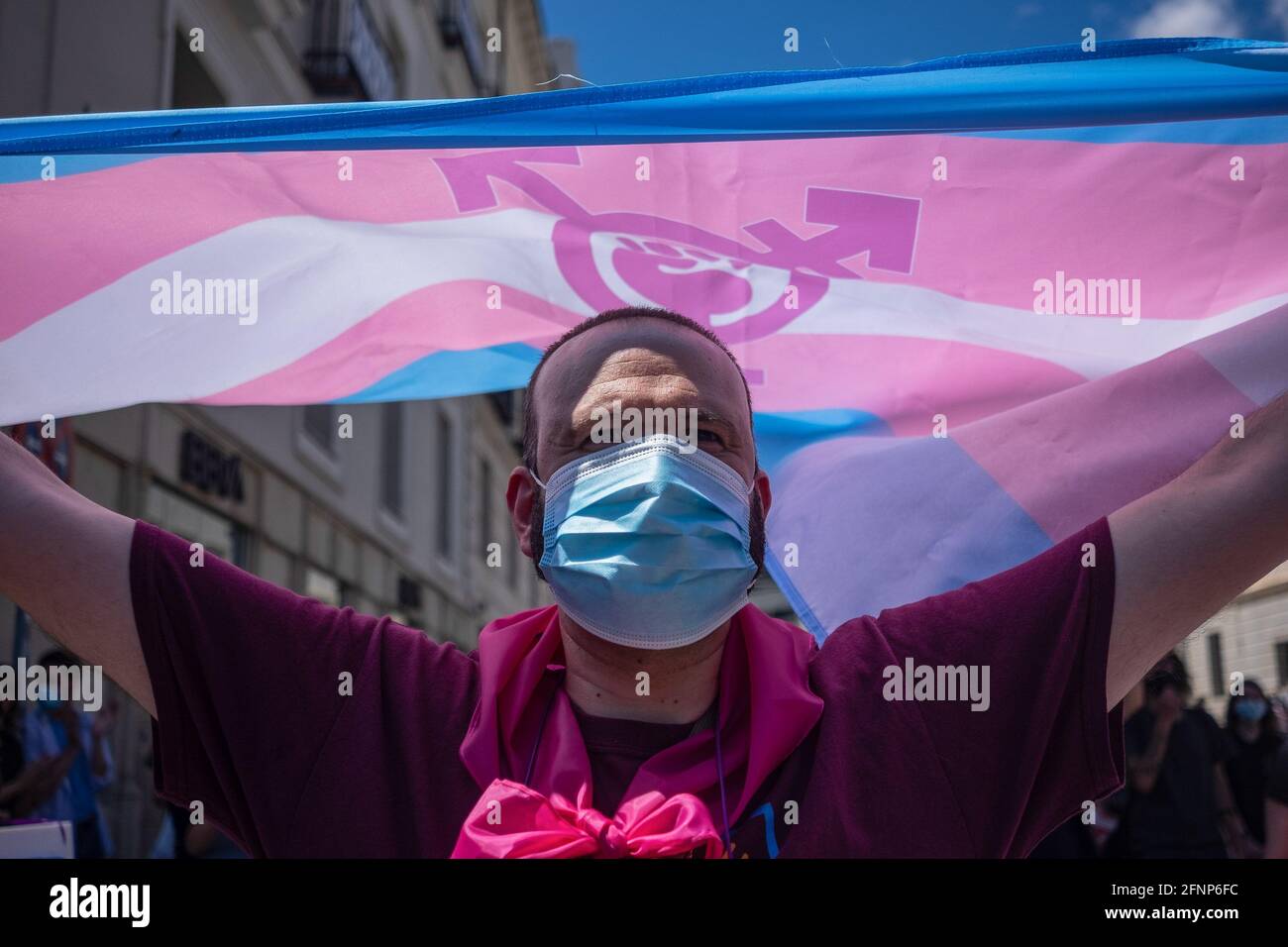 Un attivista che indossa un facemask è visto tenere la bandiera trans durante la protesta. Attivisti della Trans Community protestano al di fuori del Congresso dei deputati. La votazione per l'elaborazione della "legge statale trans" è discussa martedì 18 maggio, in occasione della plenaria del Congresso spagnolo. Foto Stock