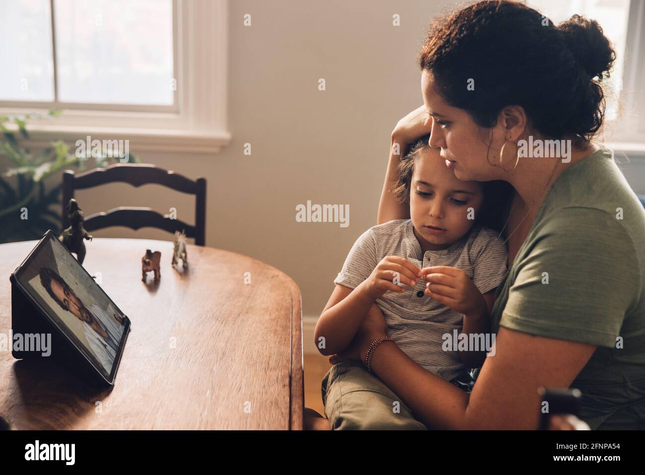 Donna con bambino malato che parla con il medico durante la videochiamata. Madre che prende la consultazione in linea dal medico per il suo figlio malato a casa. Foto Stock