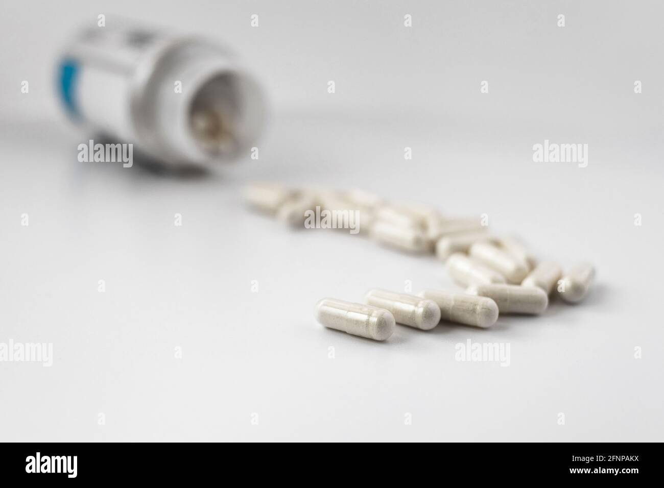 foto a fuoco selettivo delle capsule di orotato di litio, versata dal vaso. concetto dietetico. supplemento dietetico foto a profondità di campo limitata Foto Stock