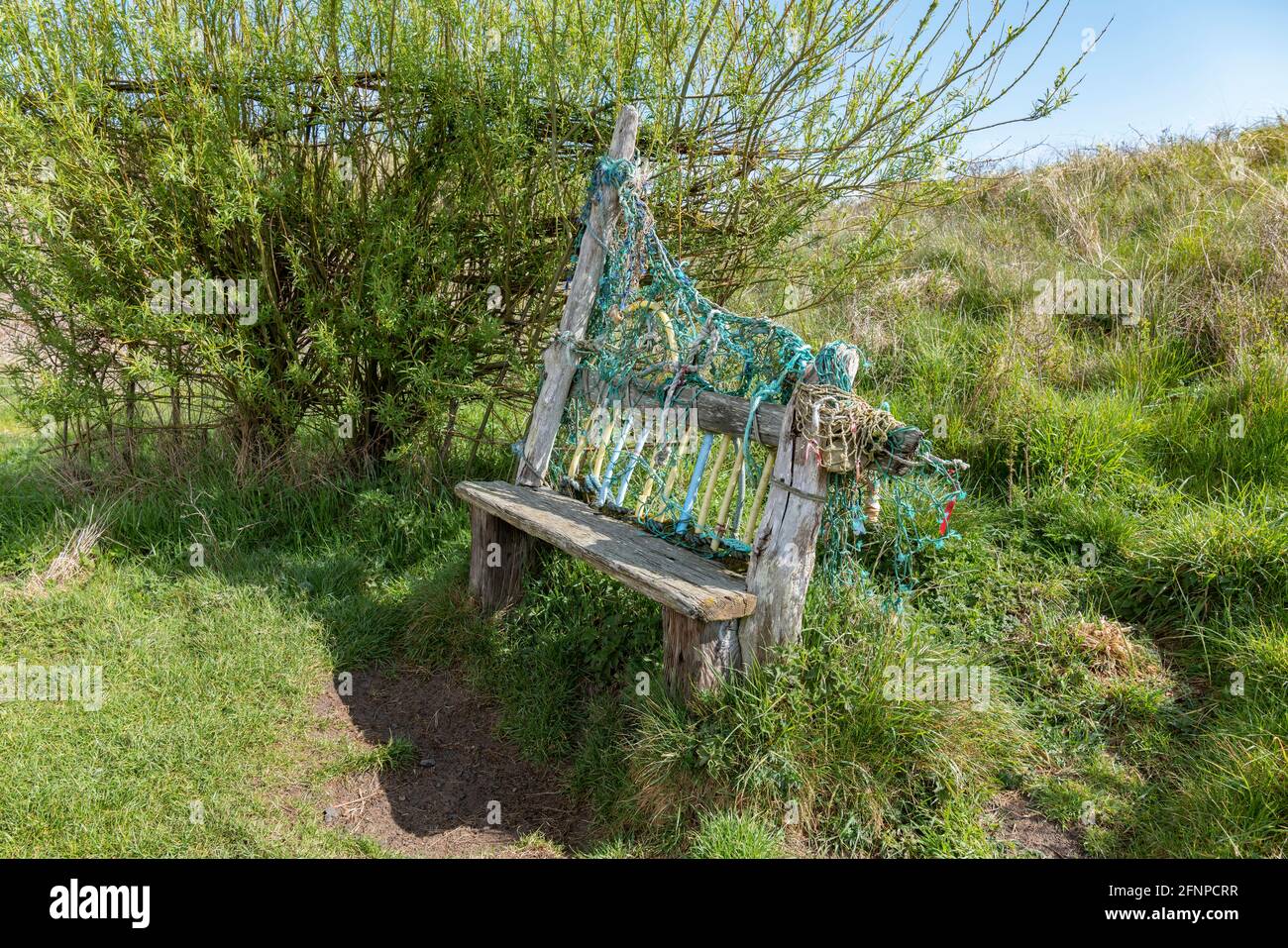 Panca e frangivento fatto da reti da pesca scartate a Newton dal mare, Northumberland, Regno Unito. Foto Stock
