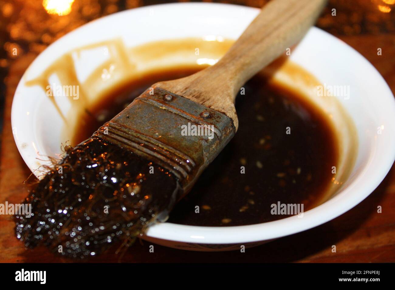 Primo piano di una ciotola di salsa al barbecue fatta in casa, con la spazzola utilizzata per stenderla sul cibo che si stese sulla parte superiore della ciotola. Foto Stock