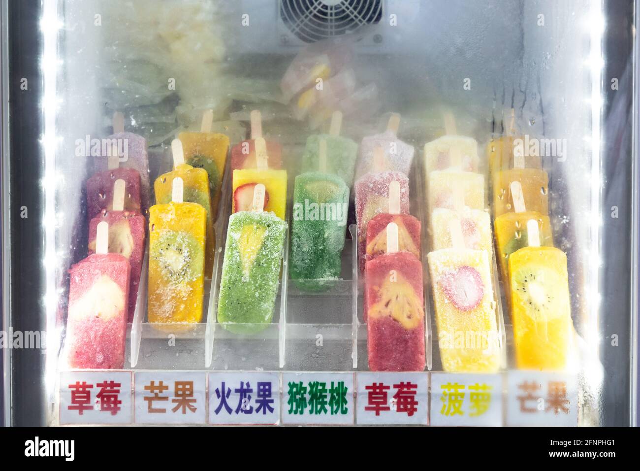 Popsicle di vari gusti e colori senza imballaggio in un congelatore. Il finestrino è appannato. Foto Stock