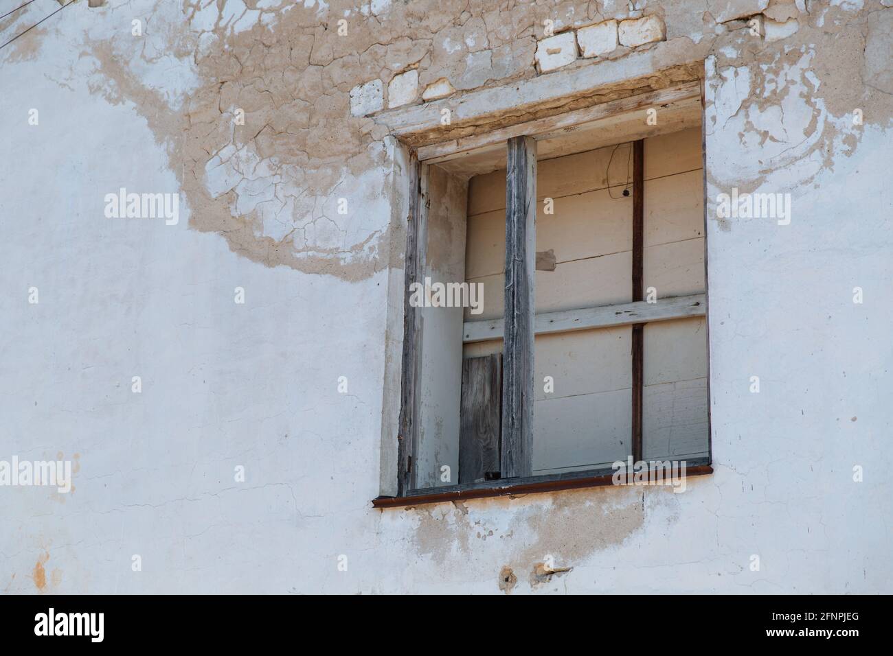 Un vecchio muro di una casa abbandonata sbriciolare con una finestra a bordo. Foto Stock