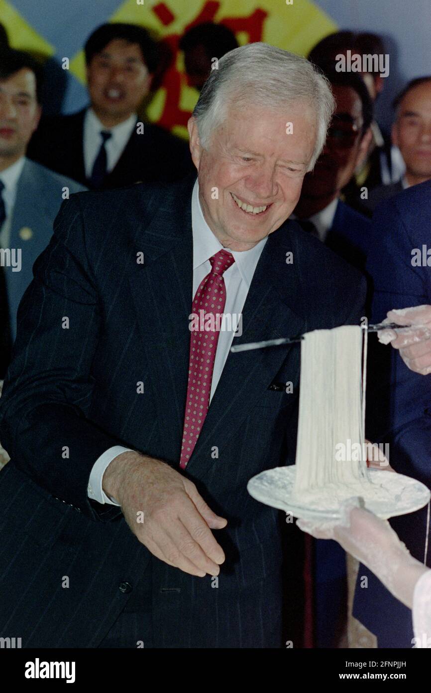 L'ex presidente degli Stati Uniti Jimmy carter sorride mentre mostra noodle fatte in casa durante una visita ad una scuola per i sordi 14 aprile 1991 a Pechino, Cina. L'ex presidente ha finanziato programmi per la formazione di istruttori speciali in Cina nel 1987 e stava verificando i progressi del suo programma. Foto Stock