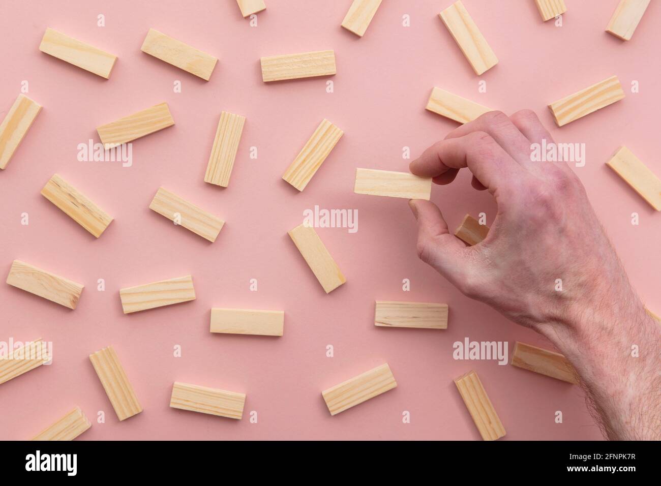 Mano che sceglie un blocco di legno da un grande gruppo. Concetto di scelta aziendale Foto Stock
